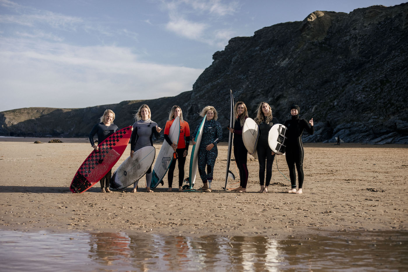 Summer Surf with Gather and Glide. 7 ladies holding surfboards, doing different poses, standing in a line